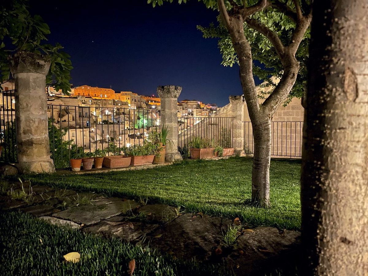 Der Garten bei Nacht, beleuchtet, dahinter die leuchtenden Sassi von Matera