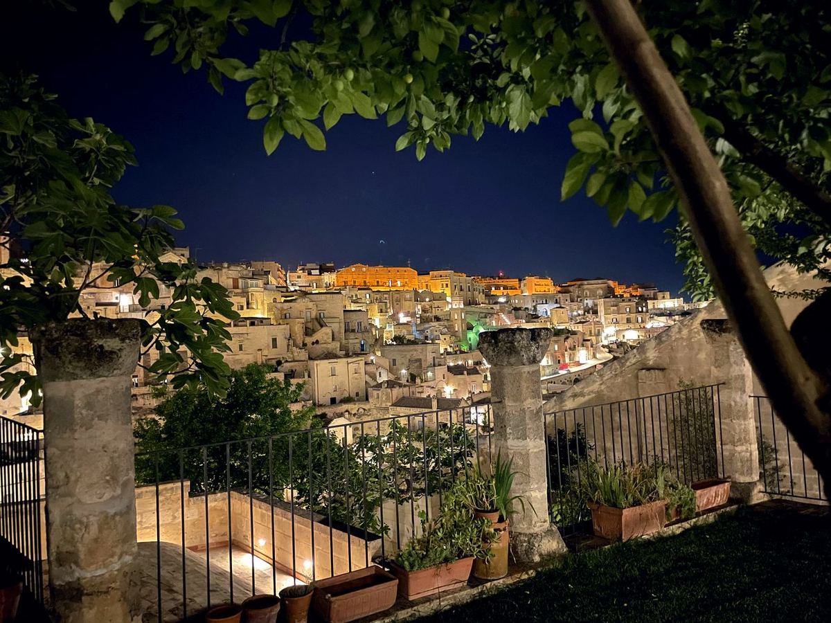 Die beleuchteten Sassi von Matera, eingerahmt von den Ästen der Gartenbäume