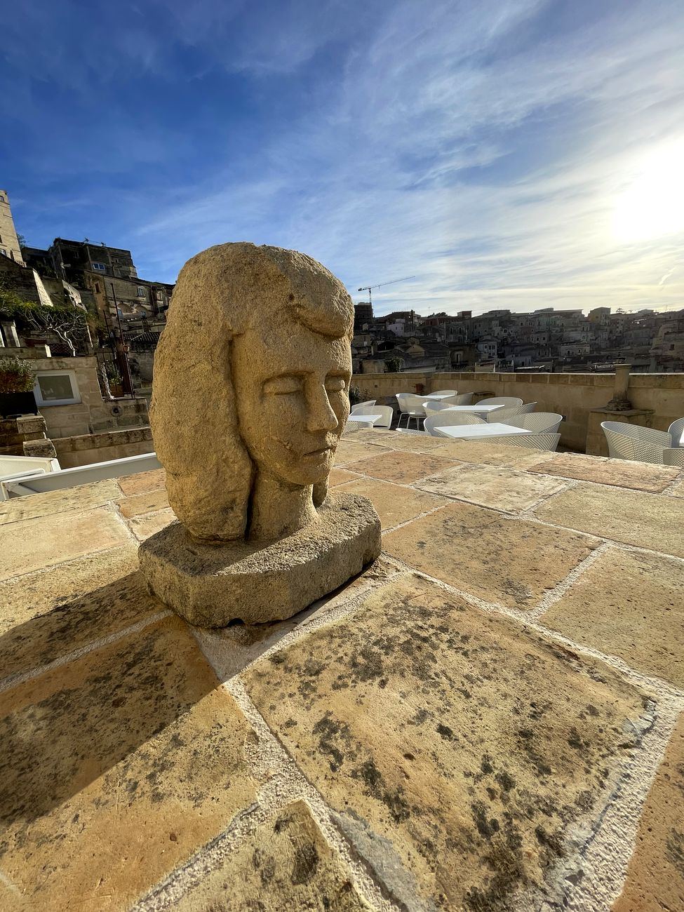 Eine Steinskulptur auf der Terrasse von Giardini di Luce, dahinter die Sassi