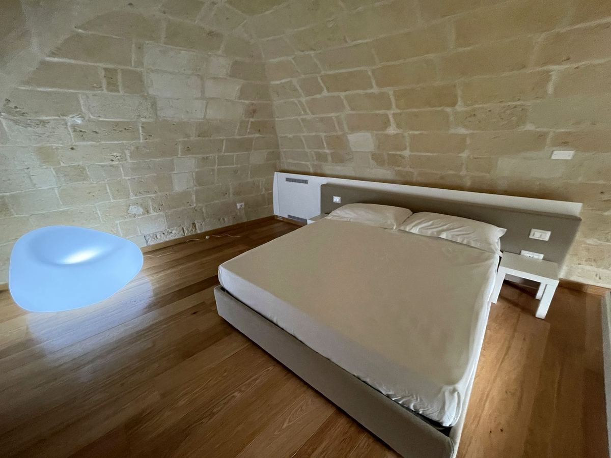 Superior Standard Suite: Doppelbett unter dem freiliegenden Steingewölbe, Holzboden und leuchtende Lampe