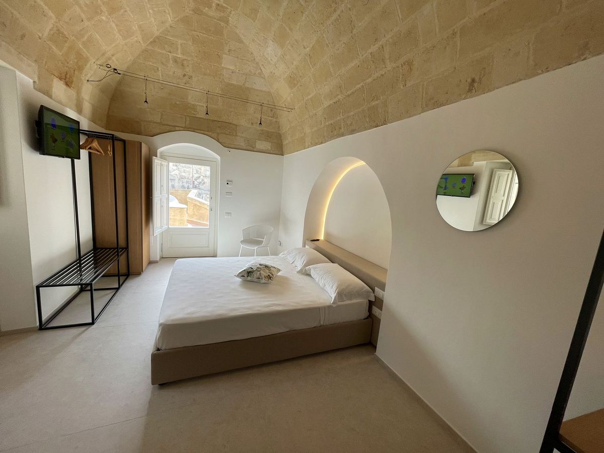 Suite mit Whirlpool: Doppelbett unter dem Tuffgewölbe, hinterleuchteter Bogen und Fenster zu den Sassi